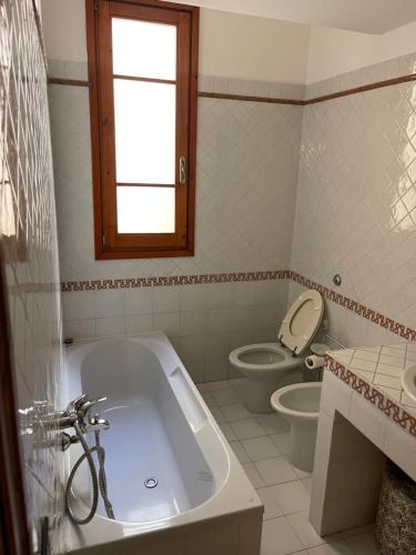 Un baño con bañera, inodoro y ventana. en Serena House, en Florencia