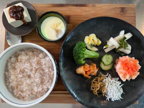 a wooden table with a plate of rice and vegetables at 'Yamaneko Hotel 'Saunas, Serenity & Feline Friends in Miyoshi