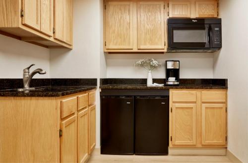 a kitchen with wooden cabinets and a black dishwasher at voco Kissimmee Orlando by IHG in Orlando
