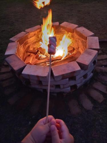 a person holding a stick in front of a fire pit at Recanto Lua de Lumiar in Nova Friburgo