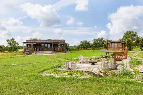 a house in the middle of a field with a bench at Meadow Vale Retreats in Screveton