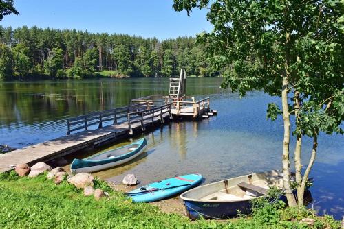 three boats are docked at a dock on a lake at Kempingas Prie Vencavų malūno in Viencavai