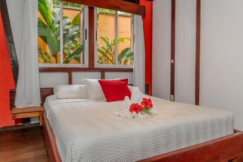 a bed with red and white pillows and a window at Namuwoki Lodge in Puerto Viejo