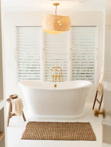 a white bath tub in a bathroom with a window at Round Hill Hotel & Villas in Montego Bay