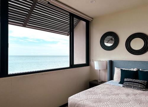 a bedroom with a large window with a view of the ocean at Golden Hour 2BR Ocean View Apt in Holbox Island