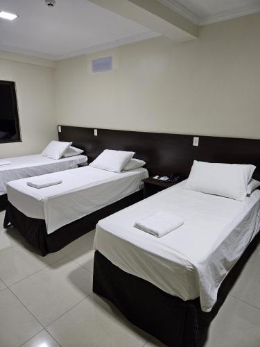 a hotel room with two beds with white sheets at Master Gold Hotel Express in Cascavel