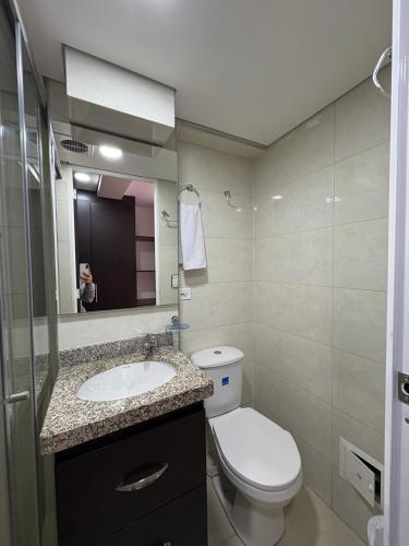 a bathroom with a toilet and a sink and a mirror at Seganis casa hotel in Bogotá