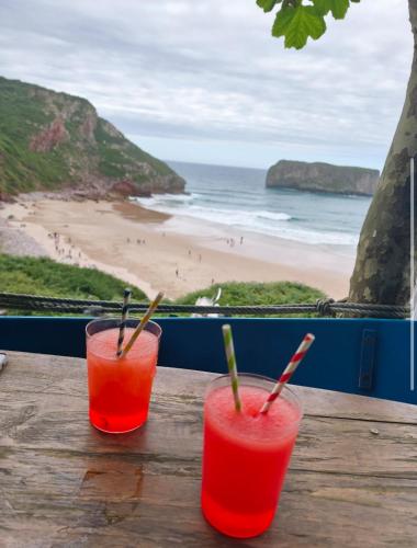 two drinks on a wooden table with a view of the beach at Casa Milu in Armiello