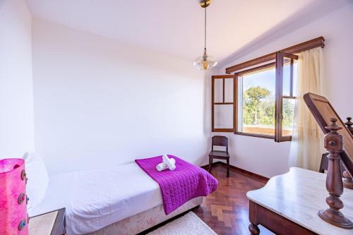 a bedroom with a bed with a purple blanket and a window at Silva Retreat Villa in São Jorge