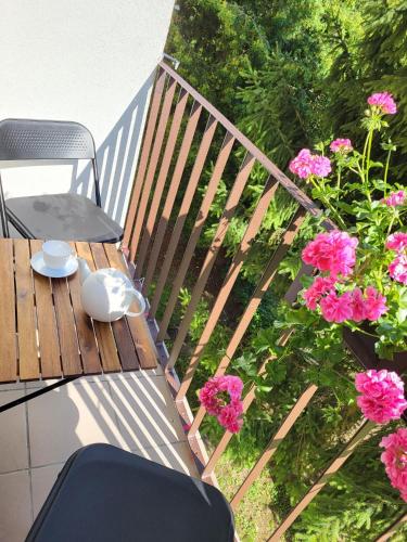 a wooden deck with a table and pink flowers at Apartament Max in Busko-Zdrój