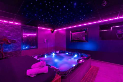 Una habitación morada con un jacuzzi con luces moradas. en Espace évasions Loft love LOVE ROOM, en Toulouse
