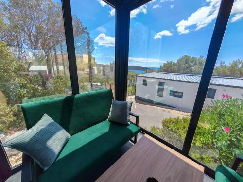 a living room with a green couch and a table at Sea view Anika by Vellaris, Luxury Mobile Home in Mali Lošinj