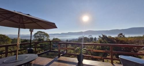 a wooden deck with a table and an umbrella at Cabana Sol do Norte in Brumadinho