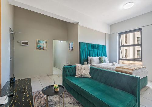 sala de estar con sofá verde y cama en Charming Studio & Backup Power, en Johannesburgo