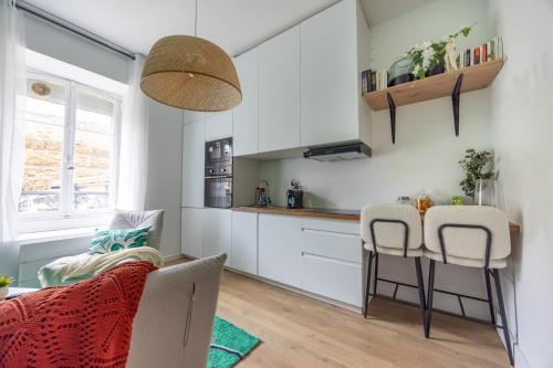 une cuisine avec des armoires blanches et une table et des chaises dans l'établissement Gîte du Bon-Secours, à Saint-Malo