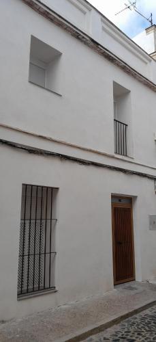 a white building with two windows and a door at A Jerez Apartamentos in Jerez de la Frontera