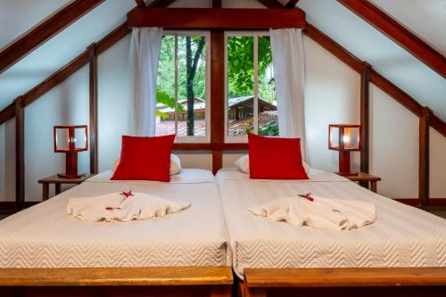 two twin beds in a room with a window at Namuwoki Lodge in Puerto Viejo