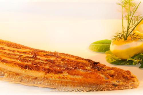 a piece of fish on a plate with a side of vegetables at Hotel Restaurant Doppeladler in Rees