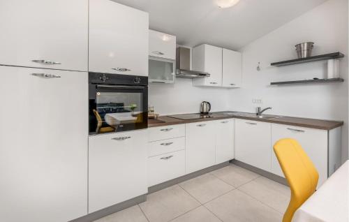a kitchen with white cabinets and a yellow chair at Beautiful Home In Dobrec With Kitchen in Dobreć