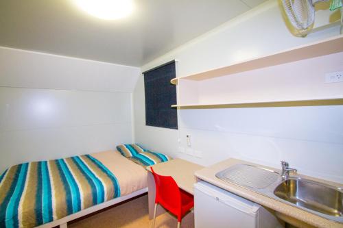 a small bedroom with a bed and a sink at AAOK Jandowae Accommodation Park in Jandowae