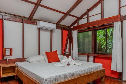 a bedroom with a bed with red walls and windows at Namuwoki Lodge in Puerto Viejo