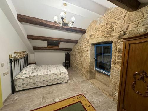 a bedroom with two beds and a stone wall at Casa Santiago in Ézaro