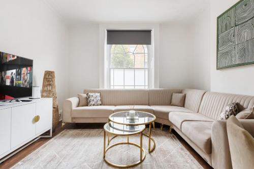 a living room with a couch and a table at Modern Flat with High Ceilings, Heart of Baker St in London