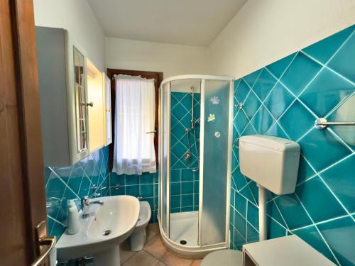 a blue tiled bathroom with a shower and a sink at Appartamento Rosè in San Teodoro