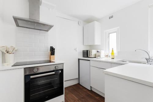 a white kitchen with a stove and a sink at Modern Flat with High Ceilings, Heart of Baker St in London