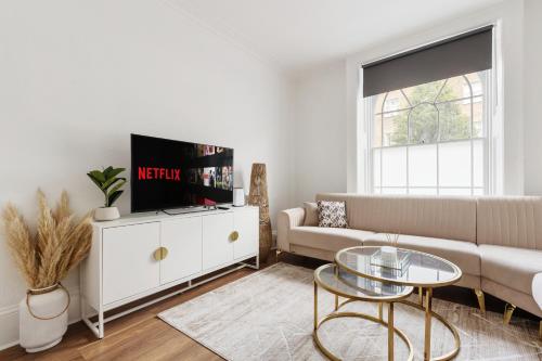 a living room with a couch and a tv at Modern Flat with High Ceilings, Heart of Baker St in London