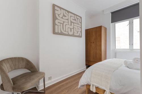 a bedroom with a bed and a chair and a window at Modern Flat with High Ceilings, Heart of Baker St in London