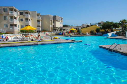 a large blue swimming pool with chairs and umbrellas at A Place At The Beach 281 in Atlantic Beach