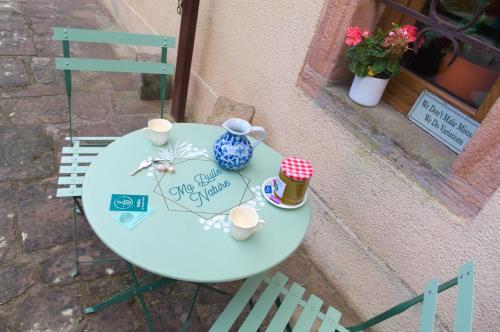 une table avec un vase bleu et des tasses dessus dans l'établissement Chambres d'hôte Odile et les cycleux Lily, à Docelles