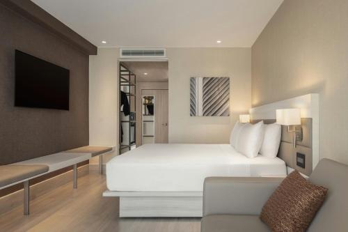 a bedroom with a white bed and a couch at AC Hotel by Marriott Santiago de los Caballeros in Santiago de los Caballeros