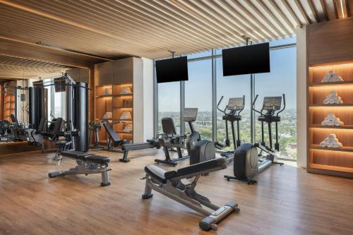 a gym with cardio equipment in a building with windows at AC Hotel by Marriott Santiago de los Caballeros in Santiago de los Caballeros
