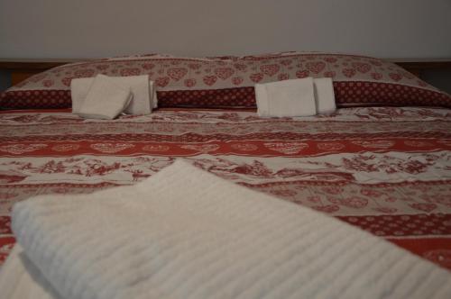 a bed with a red and white bedspread and pillows at Appartamento Batticuore in Torre Pellice