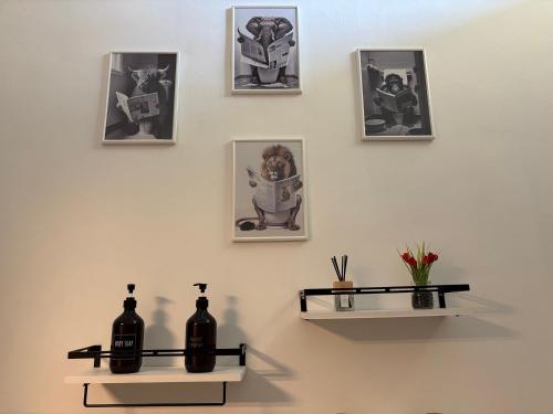 a wall with four pictures and two shelves with bottles at Sweet House in Collegno