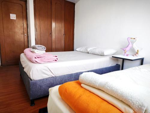 a room with two beds with towels on them at Kuyay Yachi Hostel in Bogotá