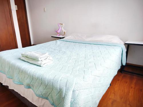 a bedroom with a bed with white sheets and a lamp at Kuyay Yachi Hostel in Bogotá
