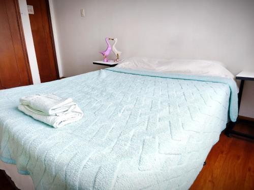 a bed with white sheets and towels on it at Kuyay Yachi Hostel in Bogotá