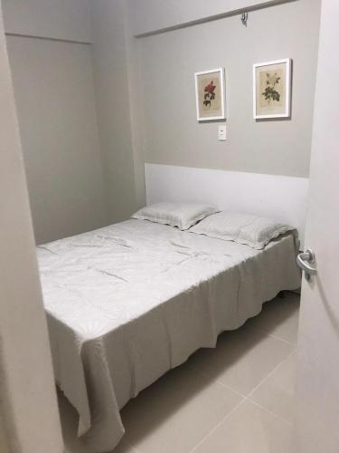 a bedroom with a bed with white sheets at Condominio Biarritz Flat Residence in São Luís