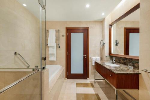a bathroom with a tub and a sink and a shower at JW Marriott Marquis City Center Doha in Doha