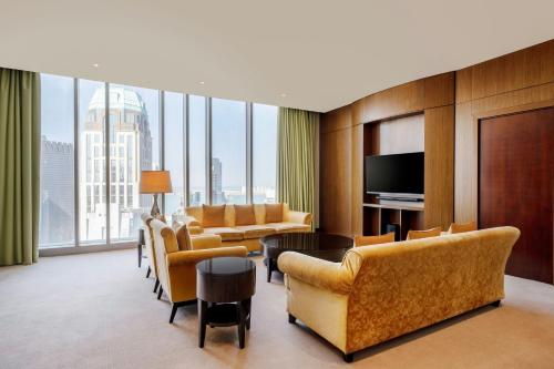 a living room with yellow furniture and a large window at JW Marriott Marquis City Center Doha in Doha