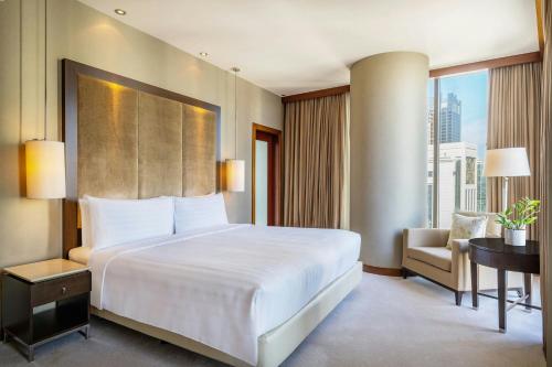 a bedroom with a large bed and a desk and a chair at JW Marriott Marquis City Center Doha in Doha