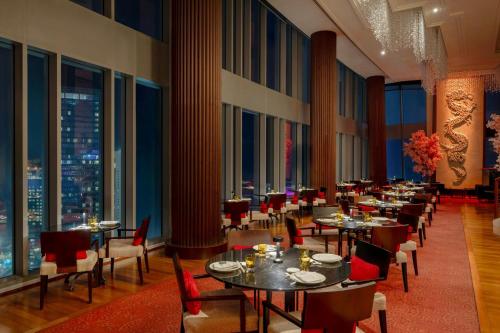 a dining room with tables and chairs and windows at JW Marriott Marquis City Center Doha in Doha