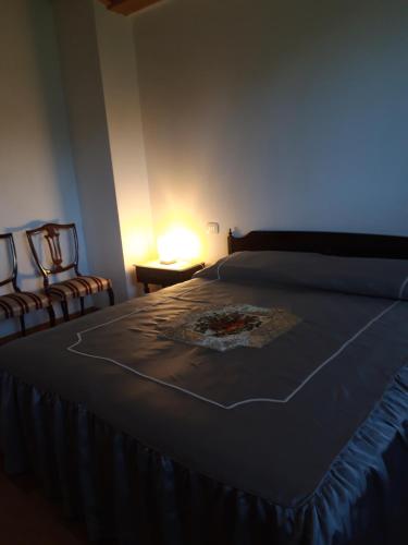 a bedroom with a bed with two chairs and a lamp at Cascina Nuova in Mombasiglio