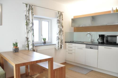 a kitchen with white cabinets and a wooden table at Ölerhof in Haag am Hausruck