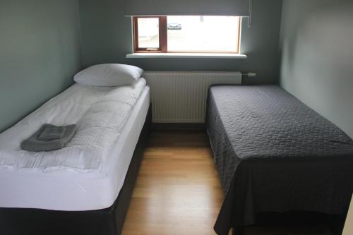 two twin beds in a small room with a window at Vesturkot horse farm Guesthouse in Selfoss