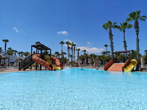 a large swimming pool with a water slide in a resort at Oasis Duna - Casa Mariposa in Corralejo