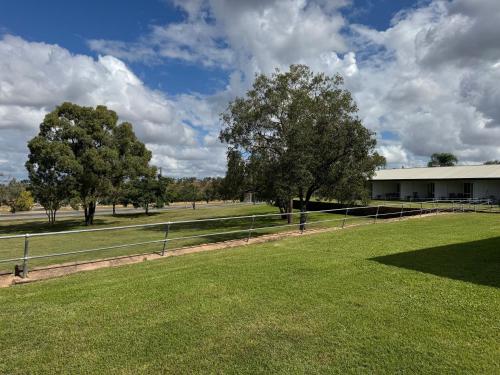 a field with a fence and trees and a building at Bulgon Lodge in Collinsville